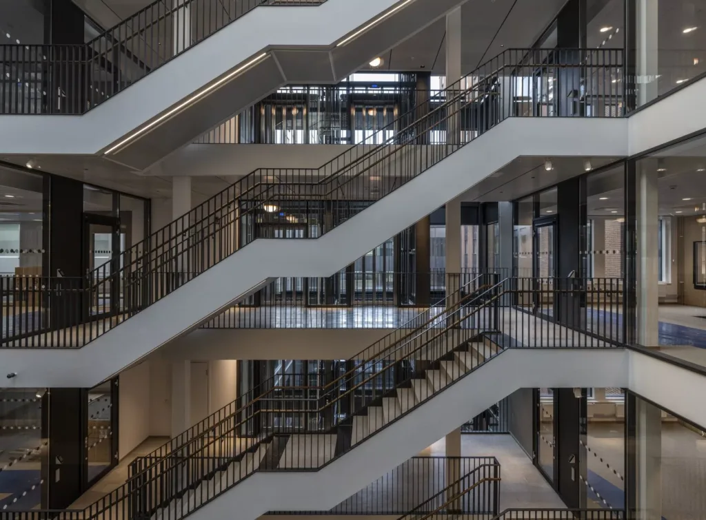 Flera våningar av trappor och gångbroar inuti en byggnad med stora glaspartier.