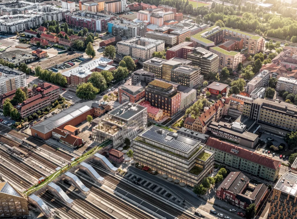 Flygbild över ett stadsområde med byggnader, parker och järnvägsspår.
