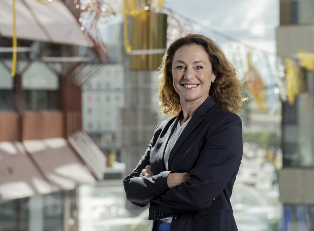 Anna Denell, hållbarhetschef på Vasakronan. står med armarna i kors framför Röda huset och Sergels torg.