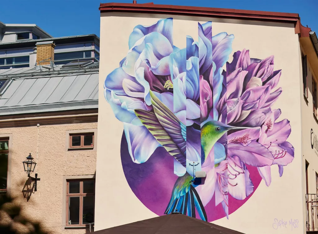 Muralmålning föreställande en fågel och blommor. På fasad i Magasinstan.