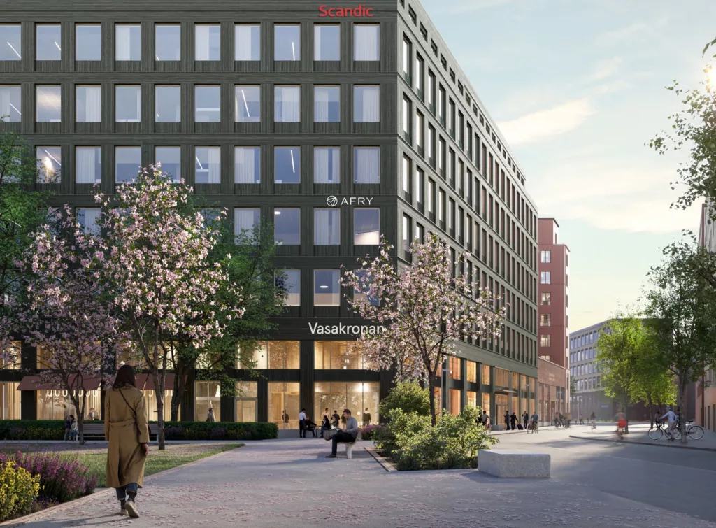 2. En grön byggnad med blommade träd framför, människor går på en bred gata. Texten "Vasakronan" är synlig på byggnaden.
