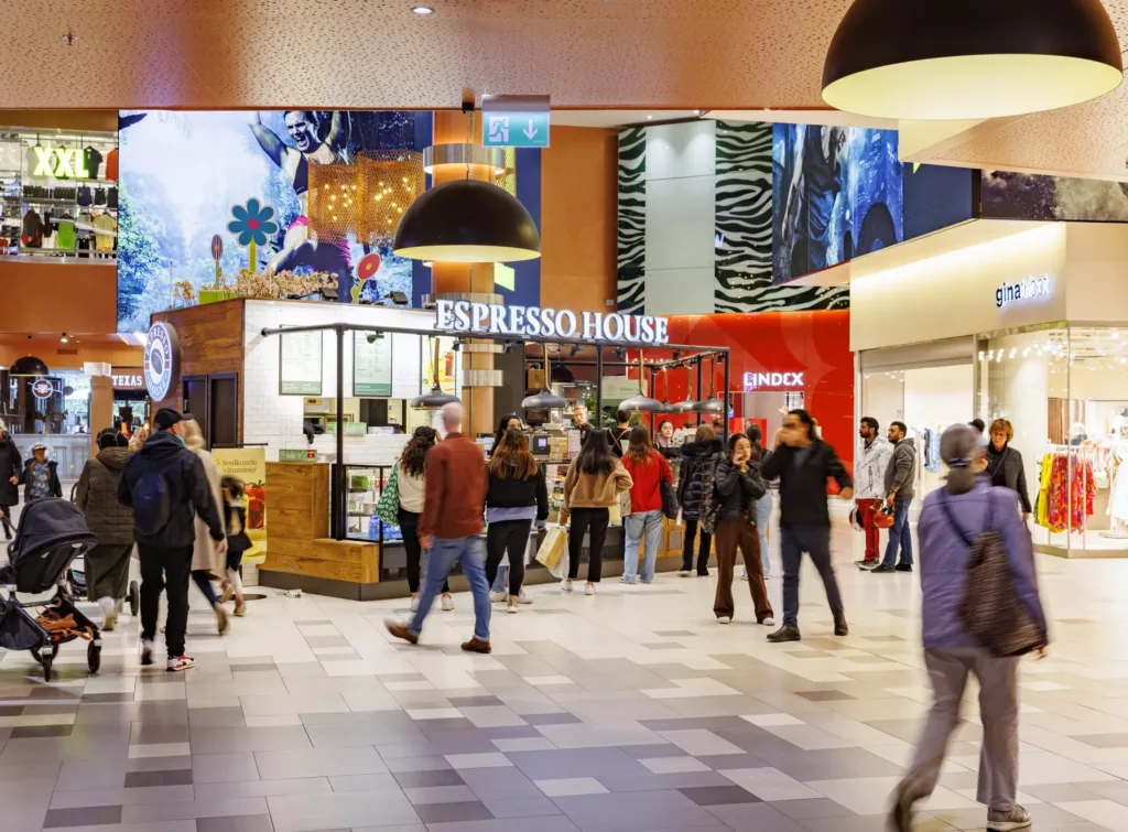 En Espresso House kafé i en livlig inomhusgalleria med människor som går och tittar runt.