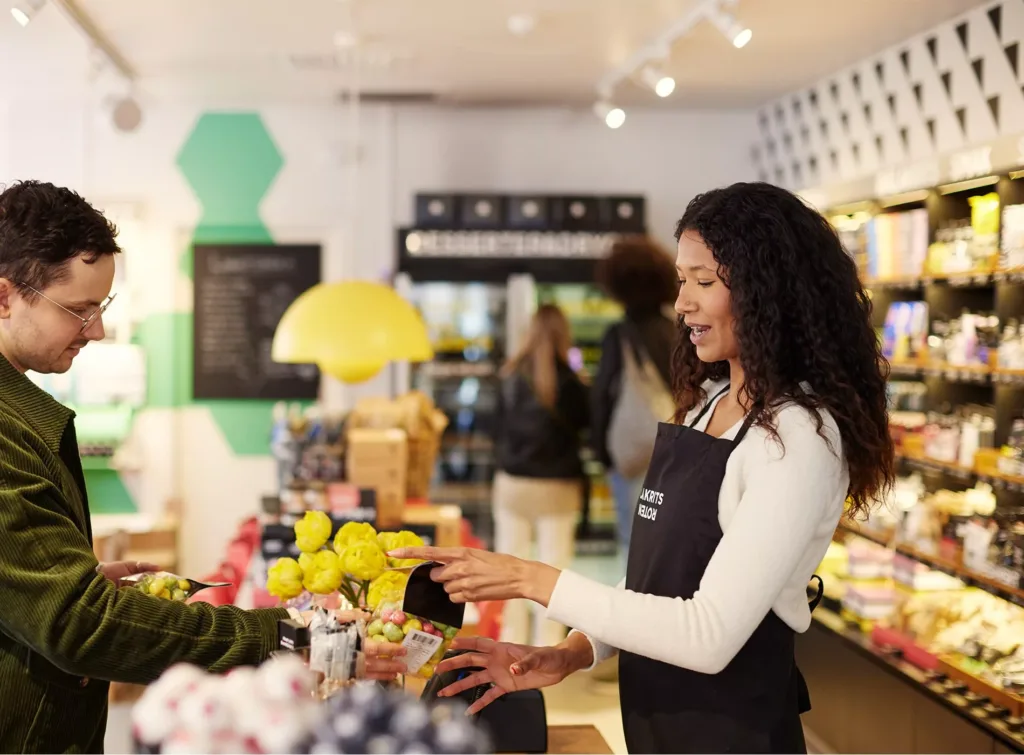 1. En kvinna i förkläde arrangerar frukt på ett bord i en butik med modern inredning.