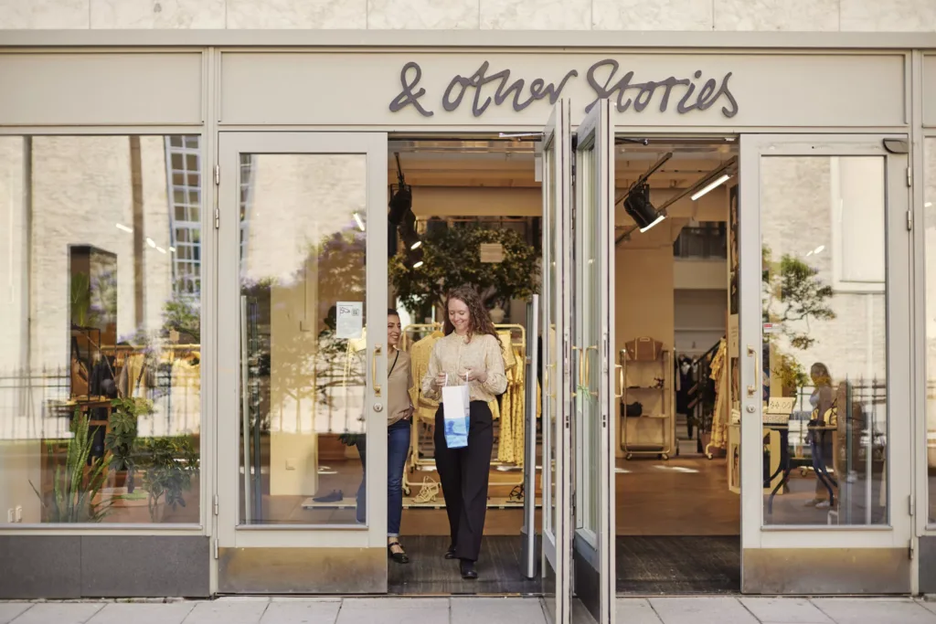 2. En person lämnar en butik med namnet "& other Stories" på skylten ovanför ingången.