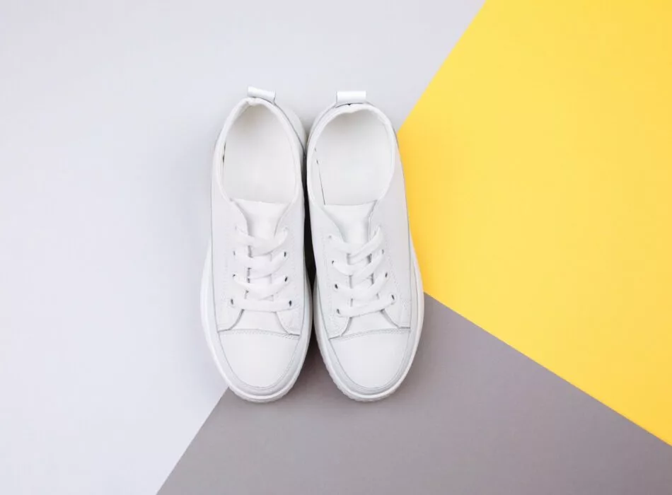 5. Ett par vita sneakers placerade på en bakgrund i vitt, gult och grått.