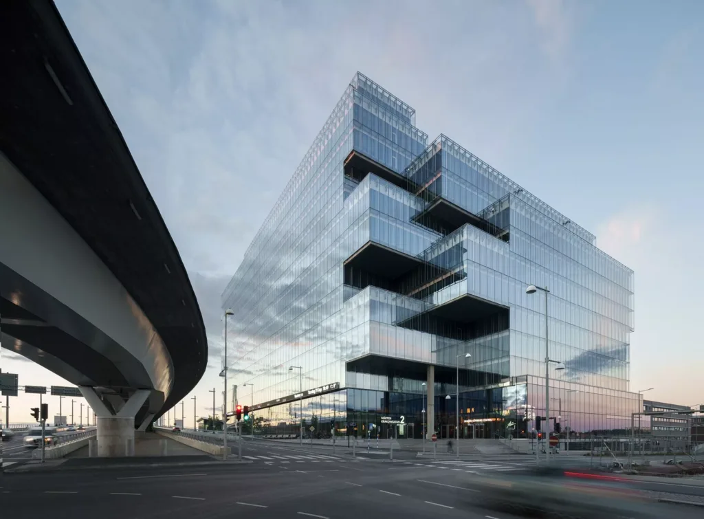 4. En modern glasbyggnad med utstickande våningsplan under en molnig himmel.