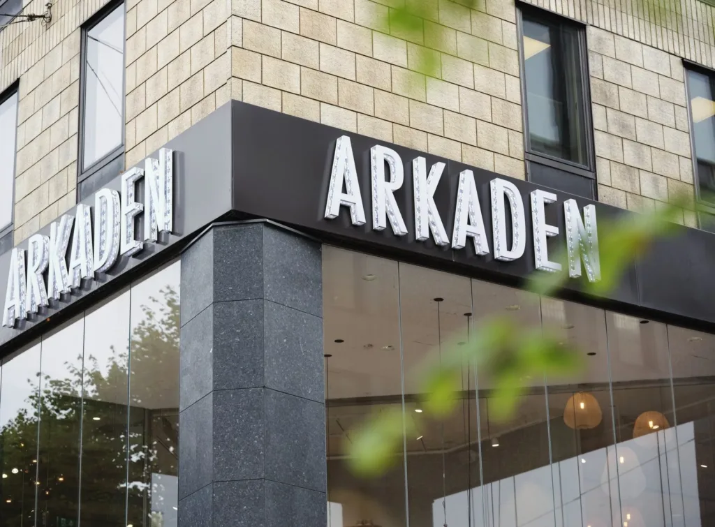 En byggnad med texten "ARKADEN" på en svart skylt vid entrén.