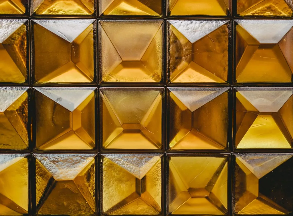 Ett mönster av gyllene, fyrkantiga glasblock med reflektioner.