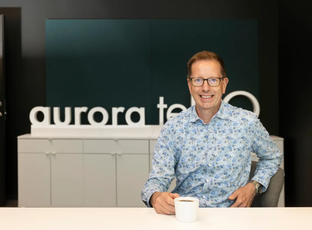Man i blå skjorta sitter vid ett skrivbord med en kaffekopp