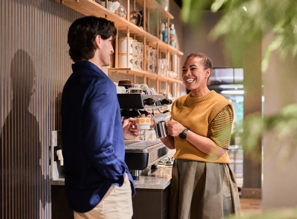 Två personer står vid en kaffemaskin.
