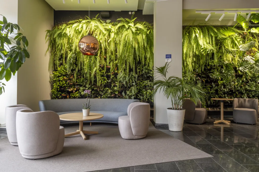 5. Ett loungeområde med grön växtvägg, soffor, fåtöljer och ett runt soffbord.