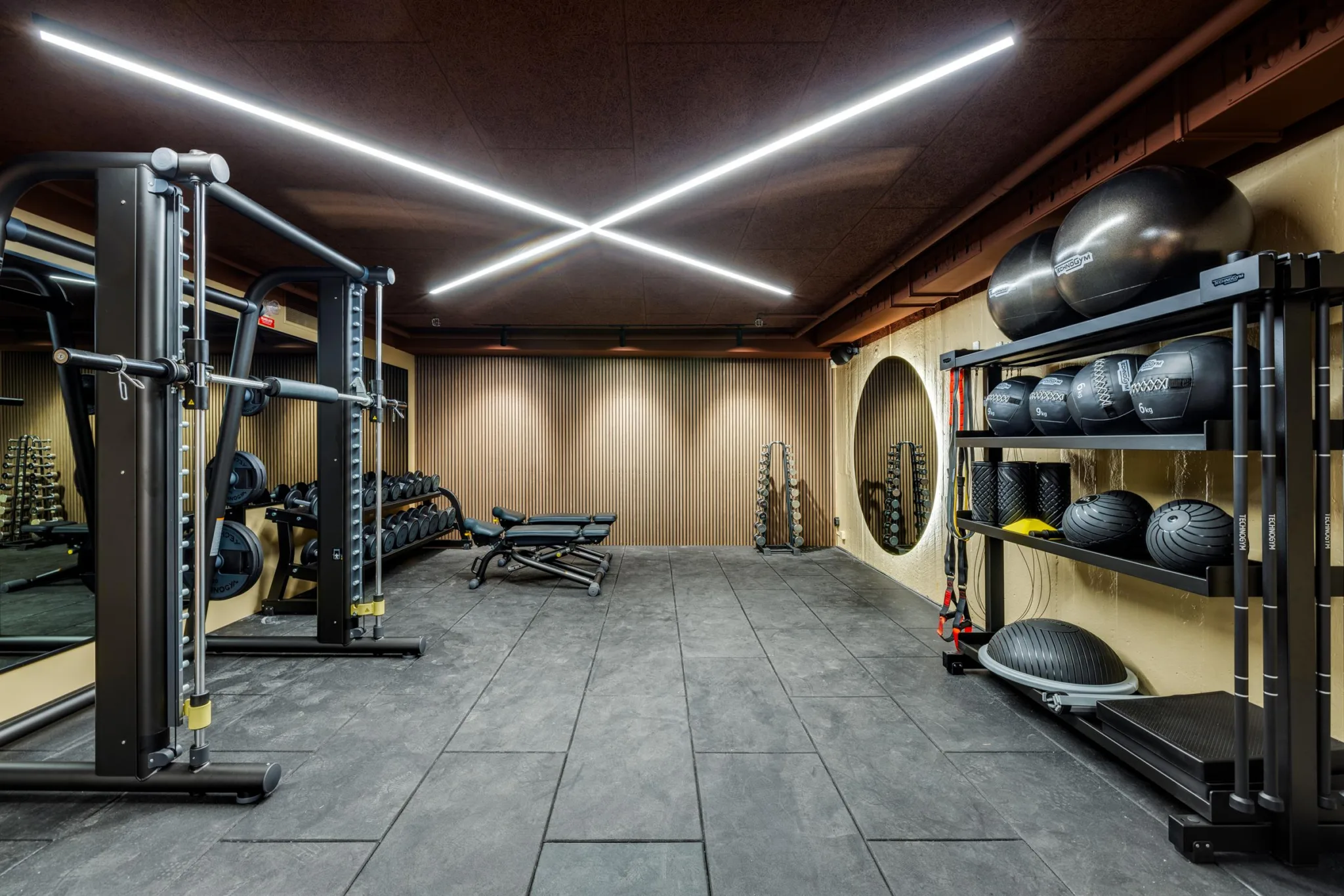 3. Ett gym med träningsutrustning, medicinbollar och modern belysning i taket.