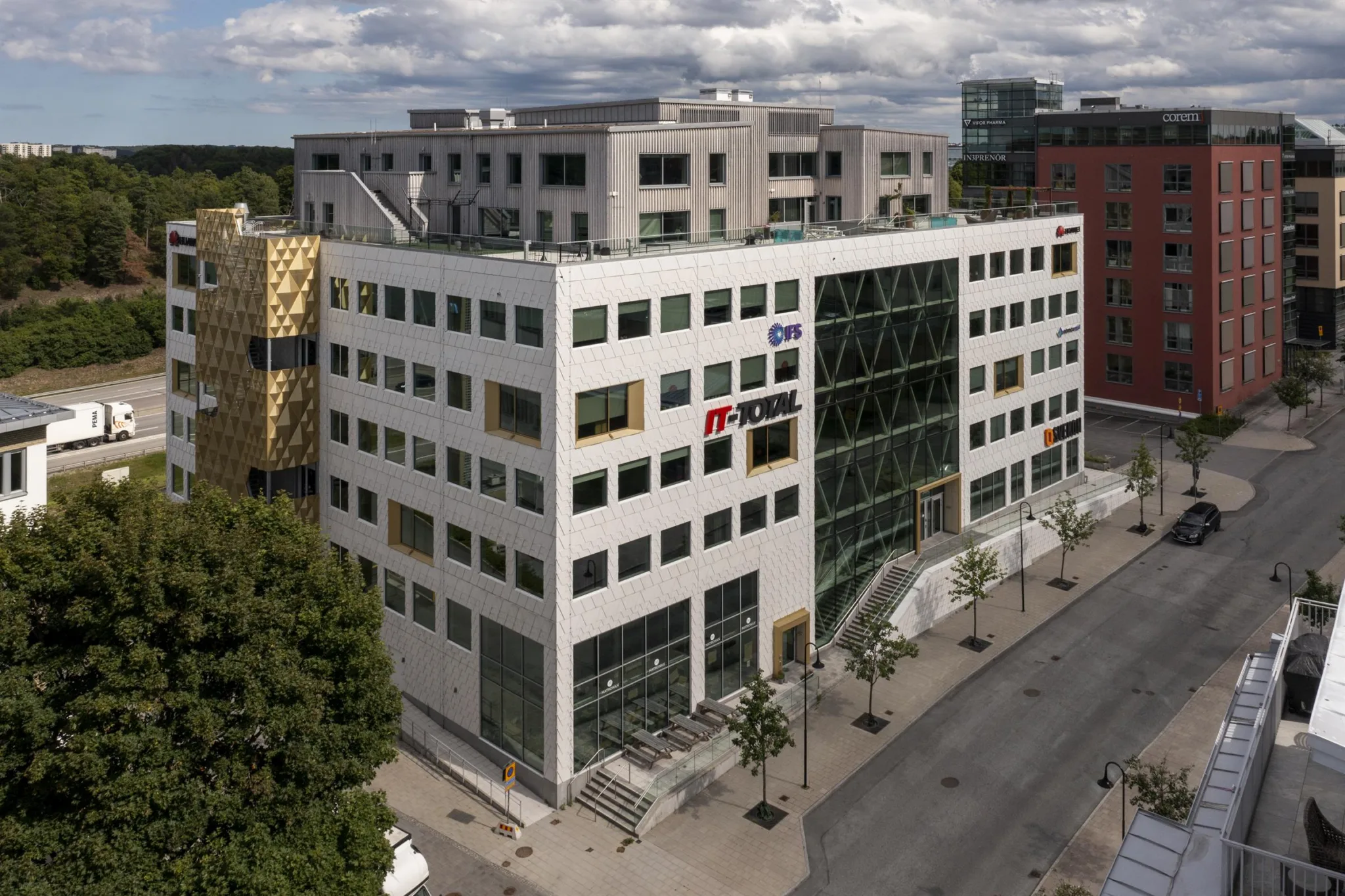 En modern kontorsbyggnad med glasfasad och flera våningar, belägen vid en stadsgata.
