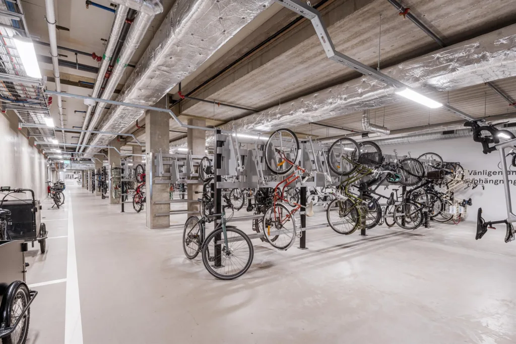Ett cykelgarage med flera cyklar parkerade i rad under ett betongtak.