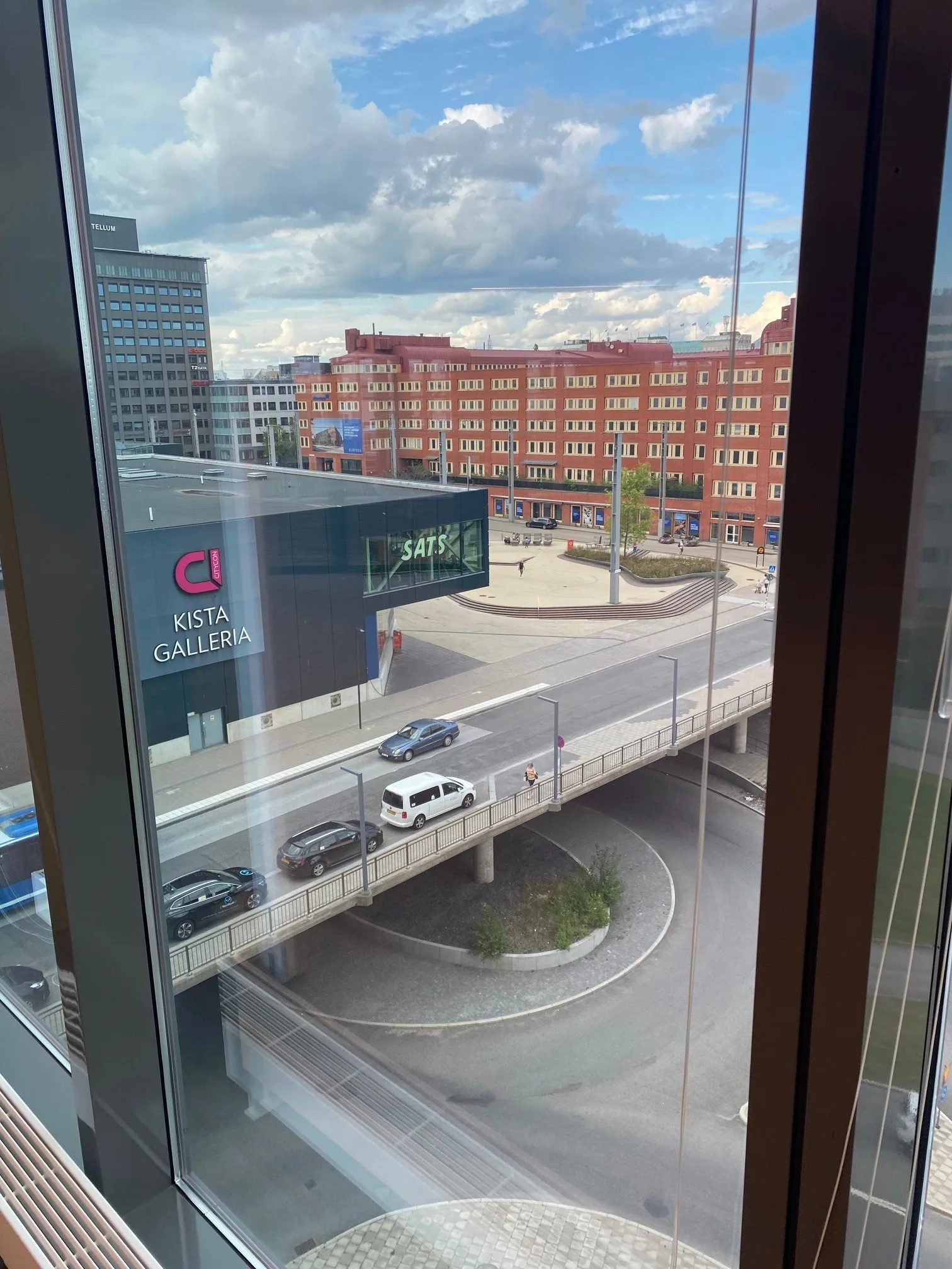 5. Utsikt genom ett fönster över en stadsgata med bilar och byggnader.