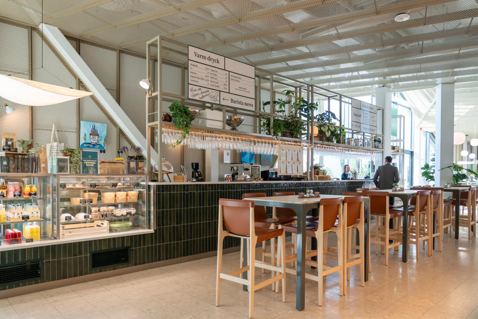 2. En ljus restaurang med höga stolar, växtdekorationer och en meny på väggen.