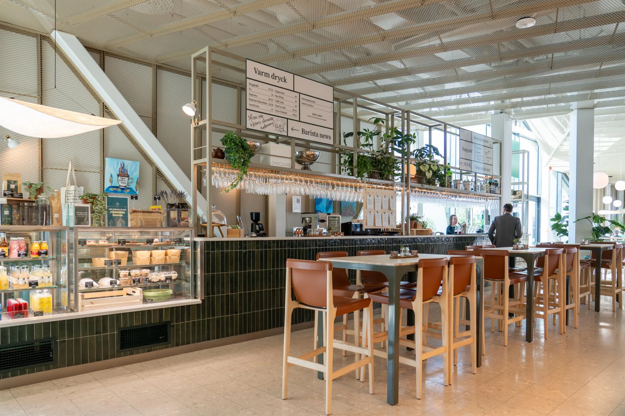 2. En ljus restaurang med höga stolar, växtdekorationer och en meny på väggen.