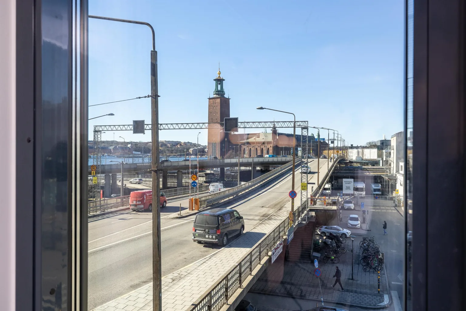 4. En stadsutsikt med en väg, bilar, gångtrafik och Stadshuset i bakgrunden under en klarblå himmel.