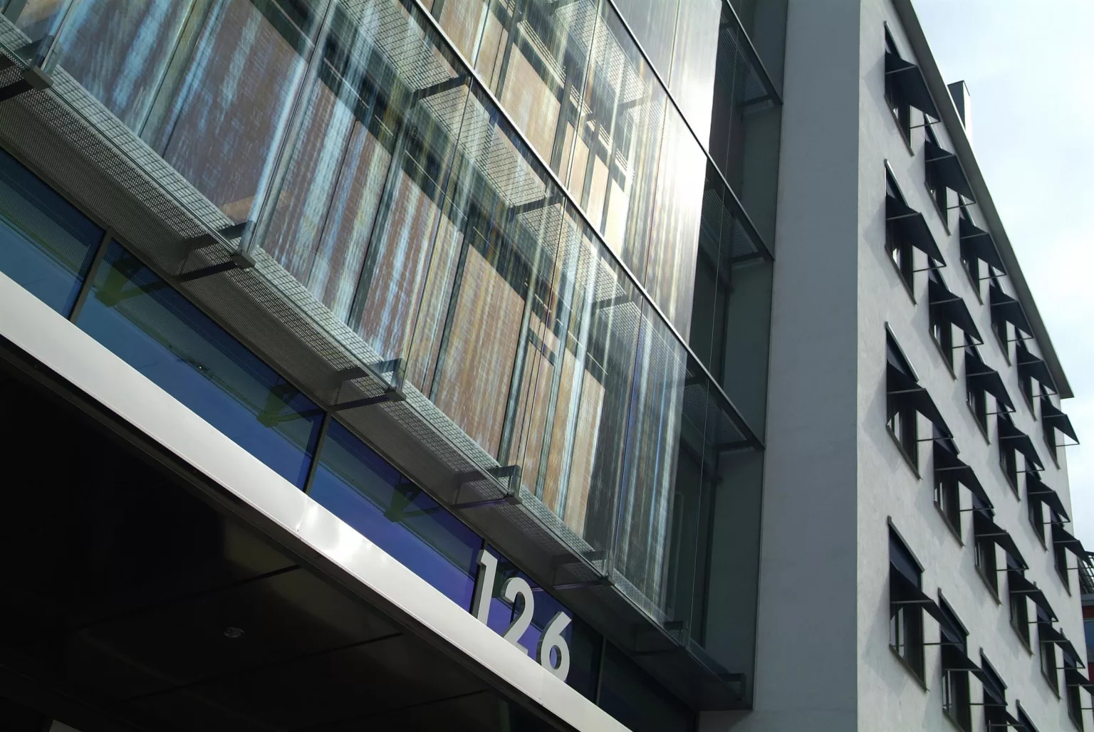 Närbild av en modern byggnads fasad med glaspaneler och siffrorna "126" synliga.