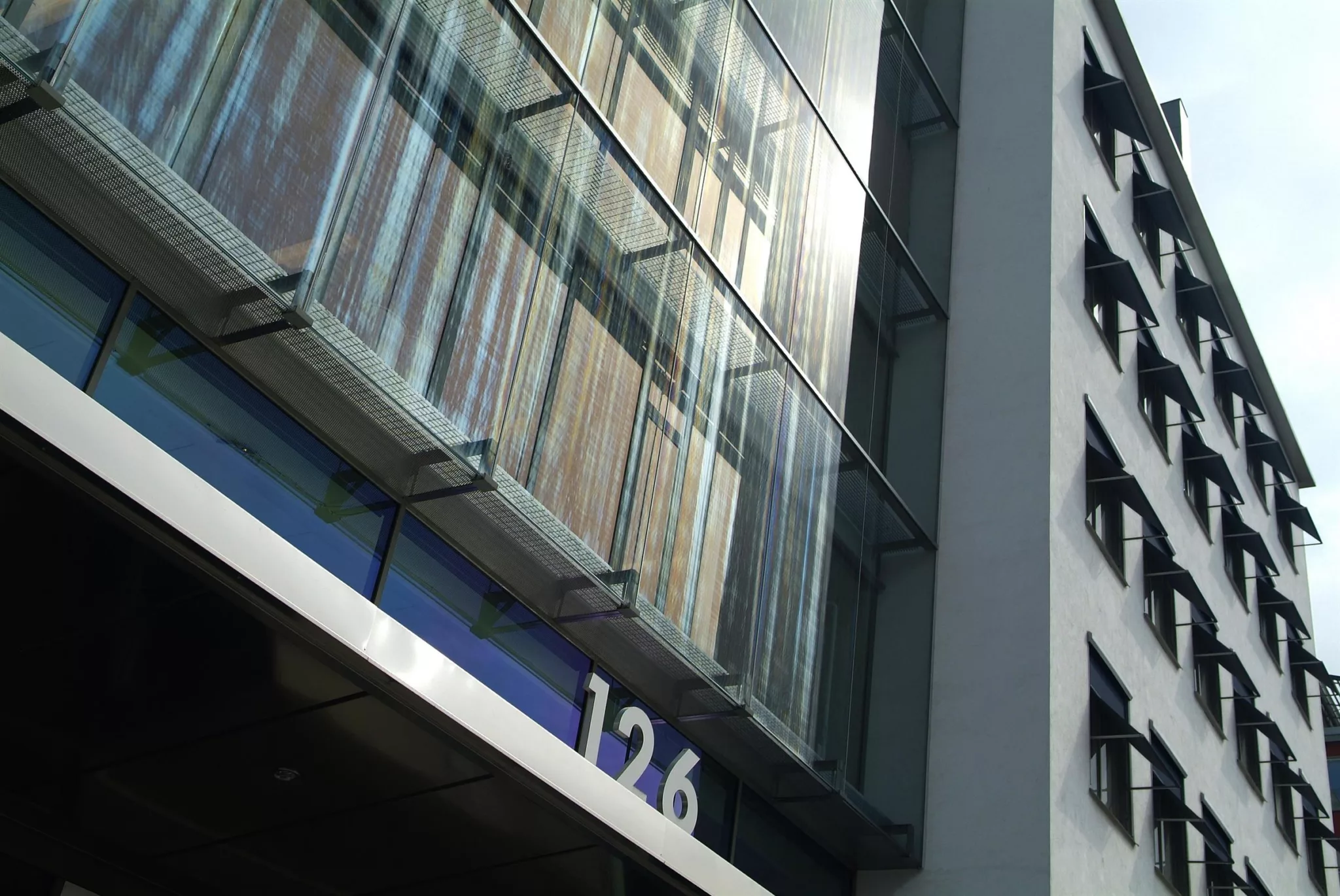 Närbild av en modern byggnads fasad med glaspaneler och siffrorna "126" synliga.