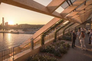 4. En takterrass med träramverk, grönska och utsikt över en stad och vatten vid solnedgången.