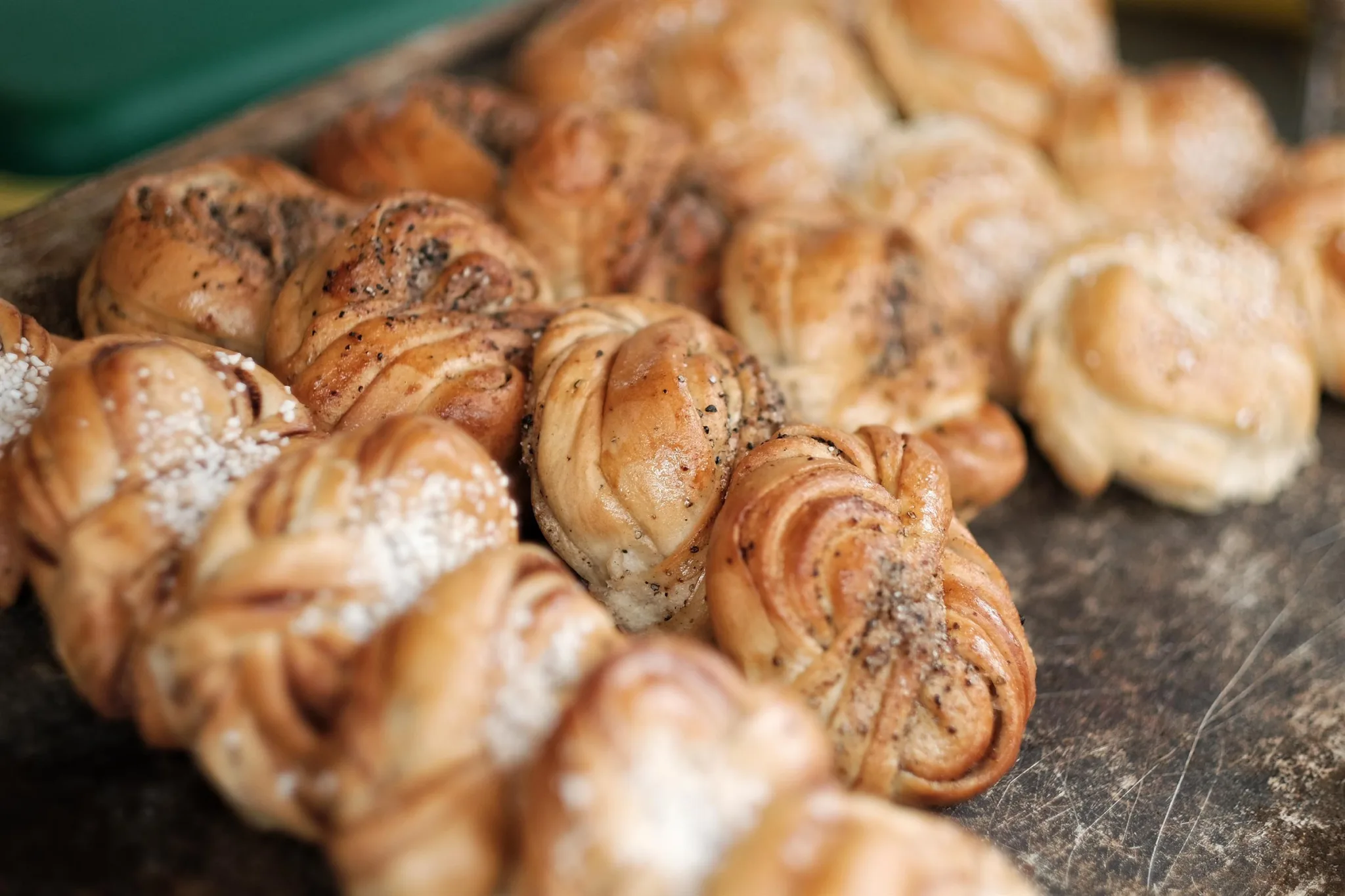 Färska kanelbullar i närbild på en bakplåt.