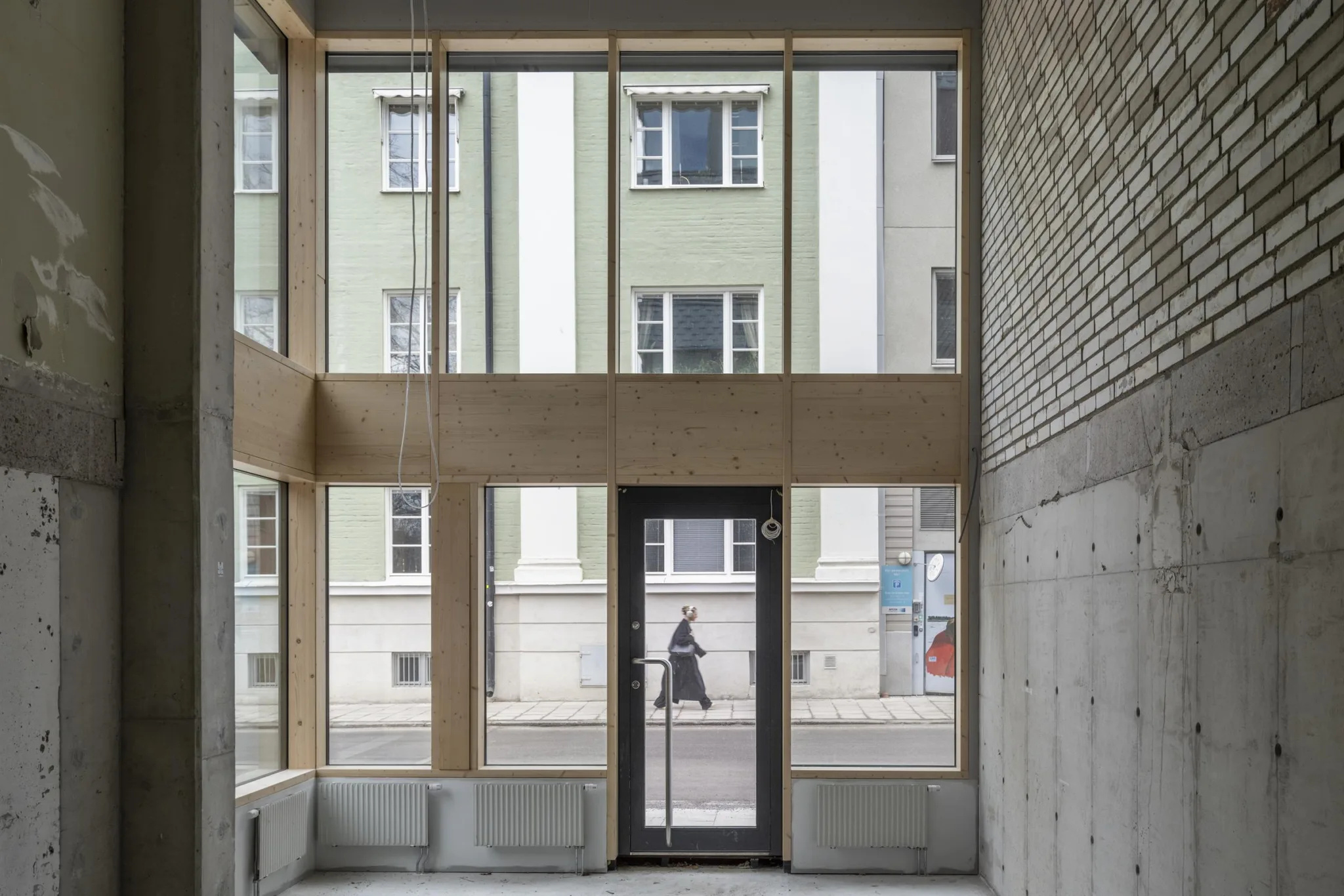 Interiör av ett modernt rum med stora glasfönster och en dörr som vetter mot gatan.