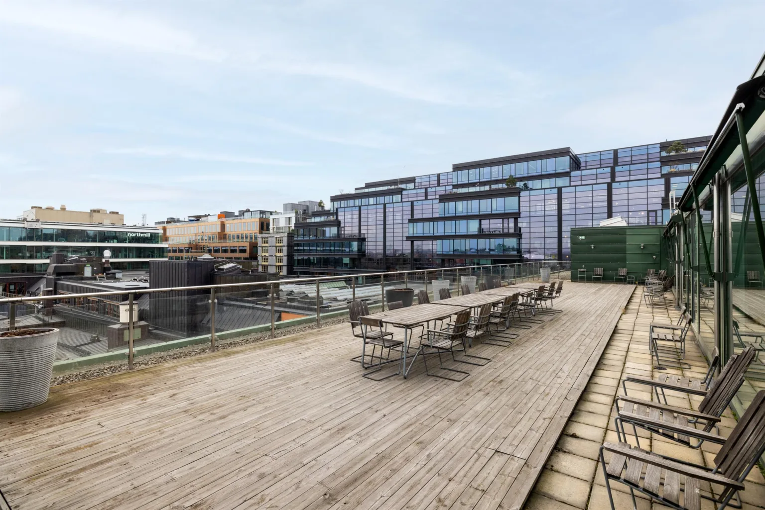 1. En takterrass med trämöbler och utsikt över moderna kontorsbyggnader.