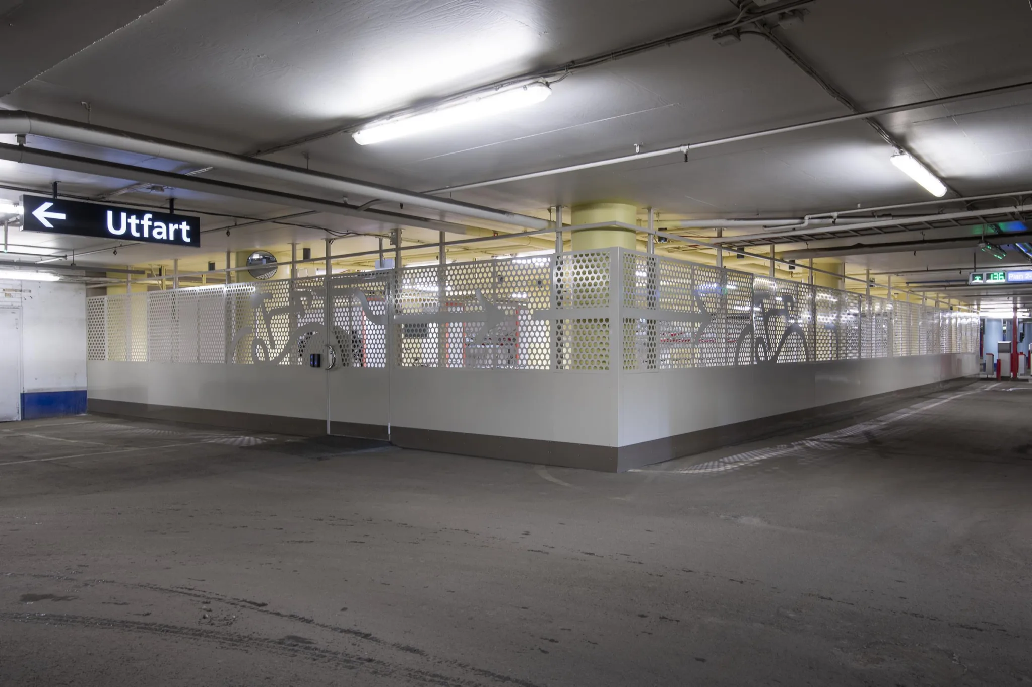 3. Ett parkeringsgarage med ett inhägnat område fyllt med teknisk utrustning, belyst av lysrörslampor.