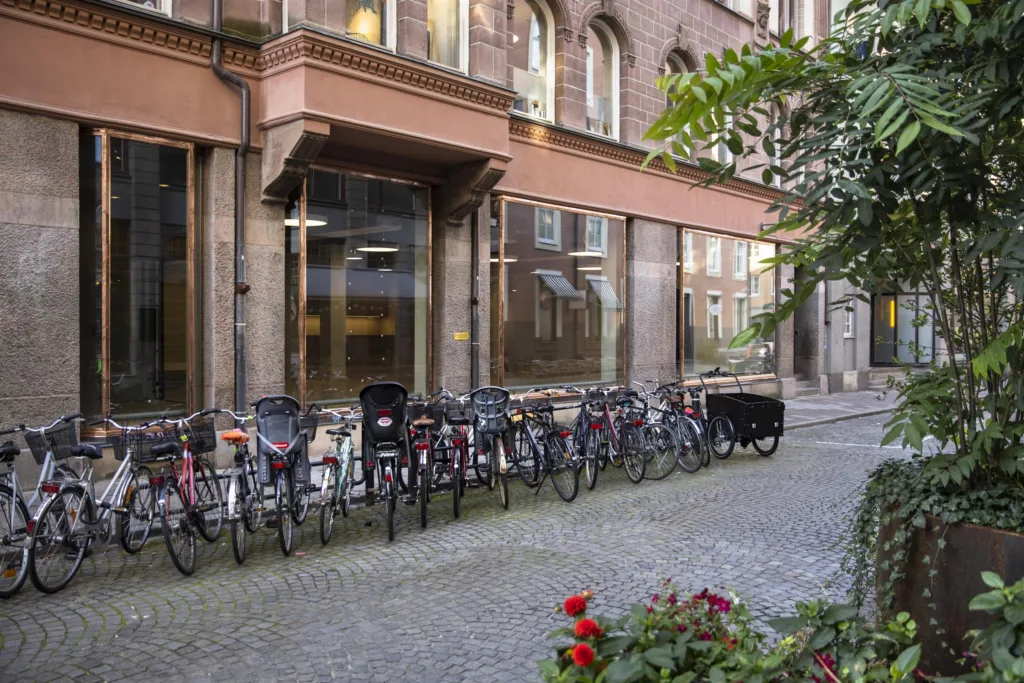 En gata med cyklar parkerade längs en stenlagd trottoar framför en gammal tegelbyggnad.
