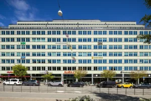 2. En stor byggnad med flera våningar, många fönster och flaggor som hänger från taket, med bilar parkerade framför.