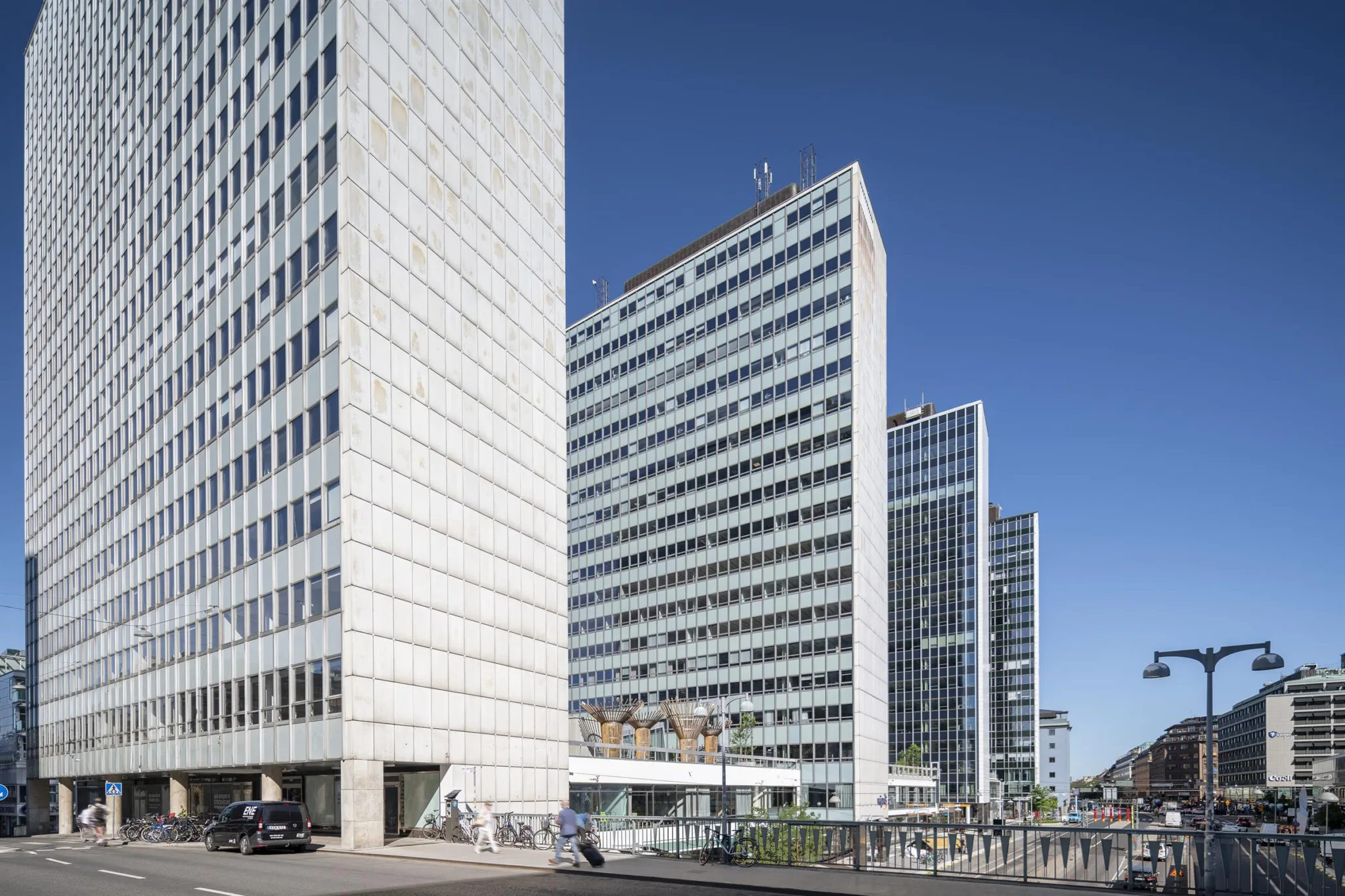 Flera höga byggnader med modern arkitektur och blå himmel i bakgrunden.