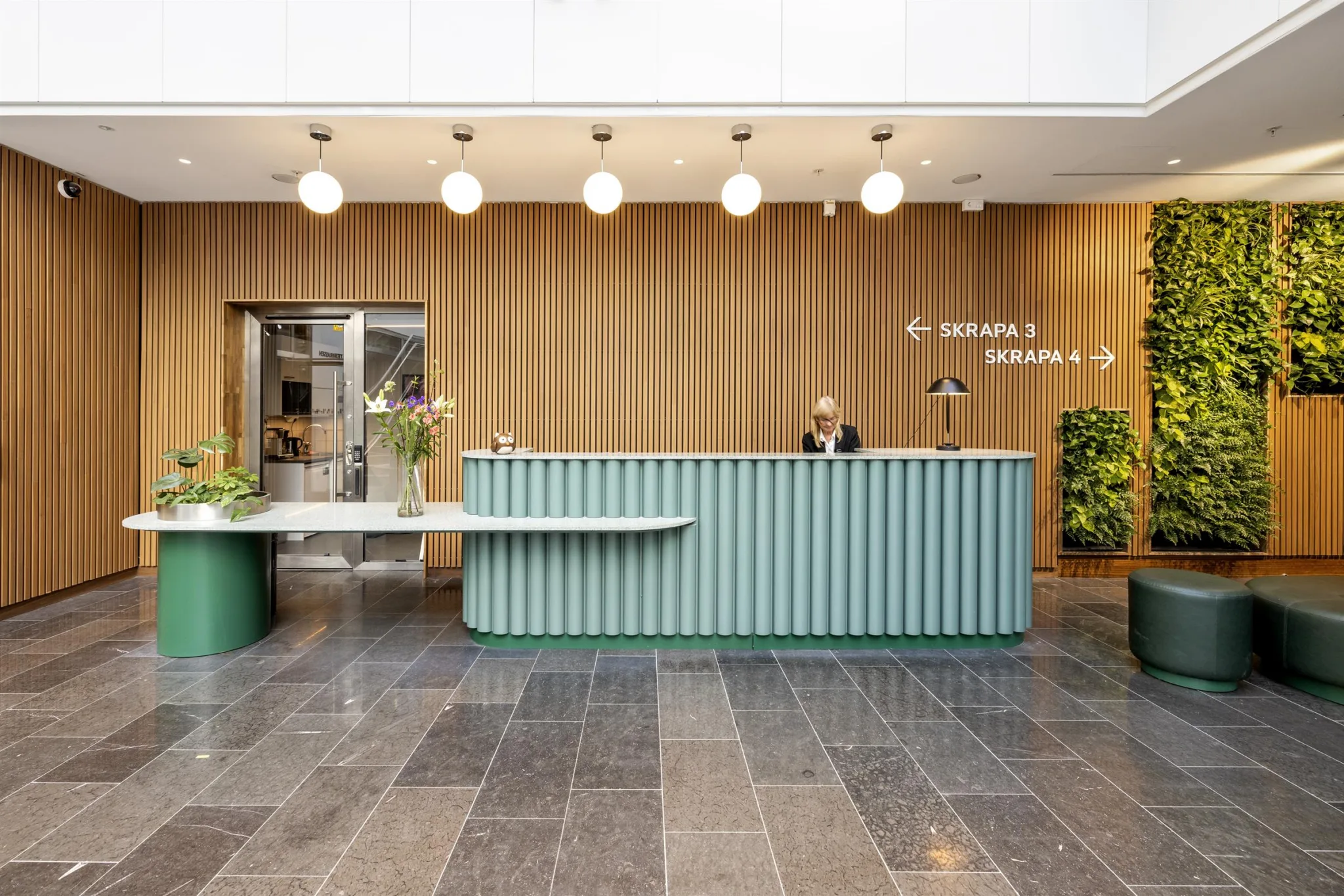 3. En reception med en ljusblå disk, en vägg av träpaneler i bakgrunden och skyltar som visar riktningar.