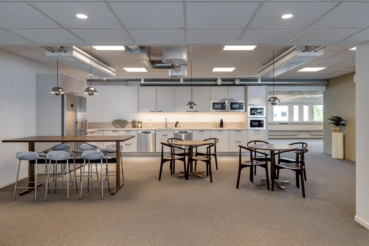 Ett öppet kök med sittgrupper, höga bord och modern köksutrustning.