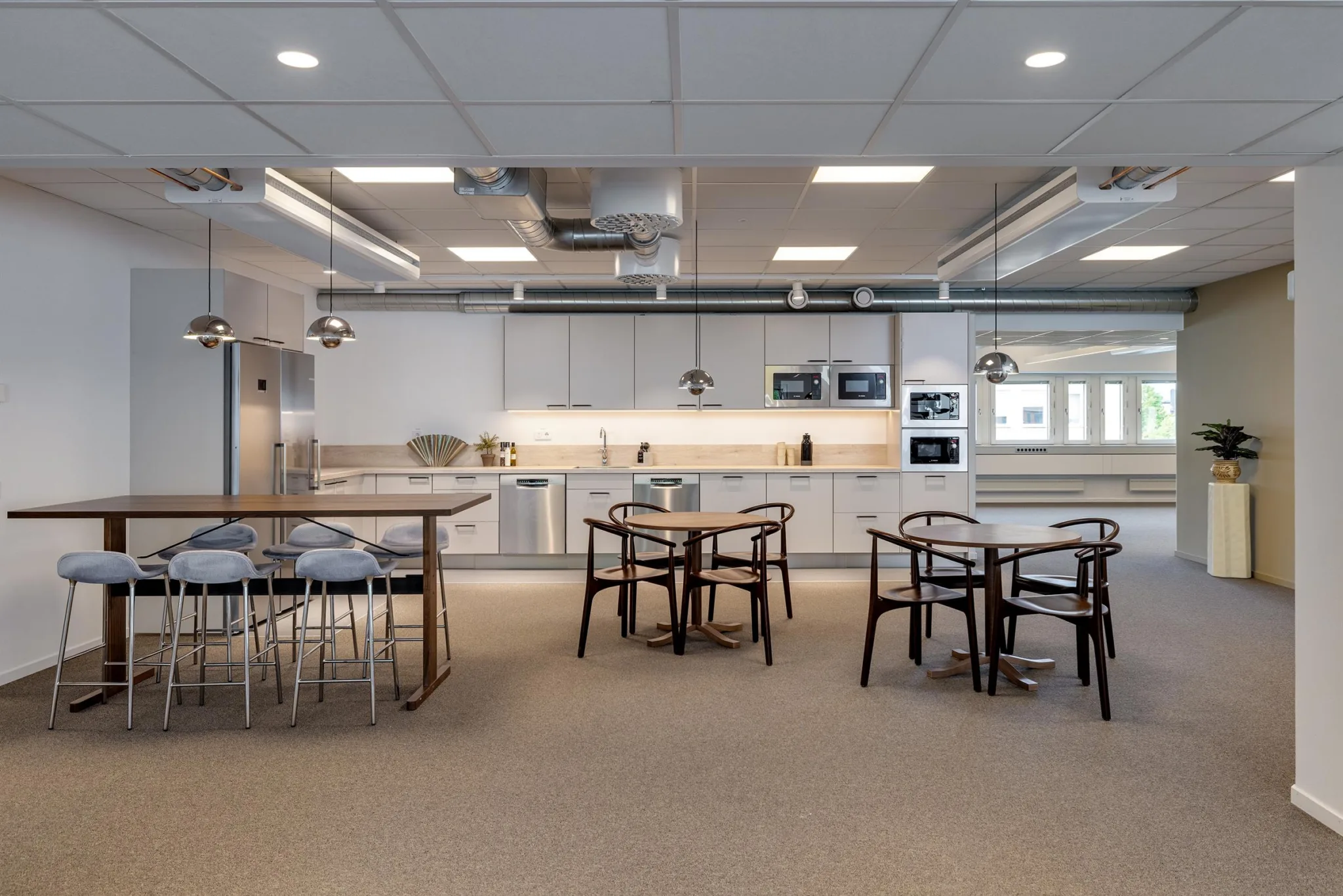 Ett öppet kök med sittgrupper, höga bord och modern köksutrustning.