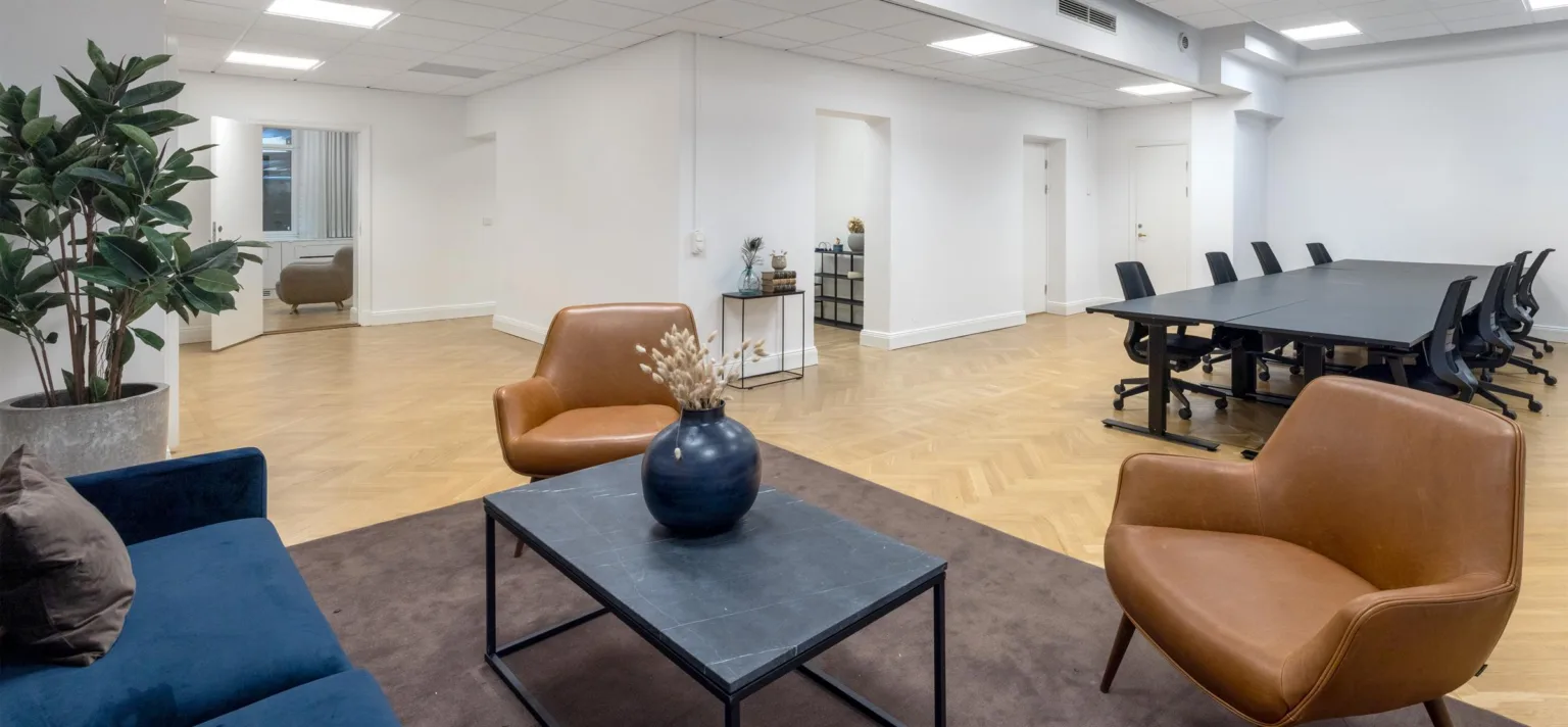 5. Ett väntrum med orange fåtöljer, ett bord med blå vas och ljusa väggar.