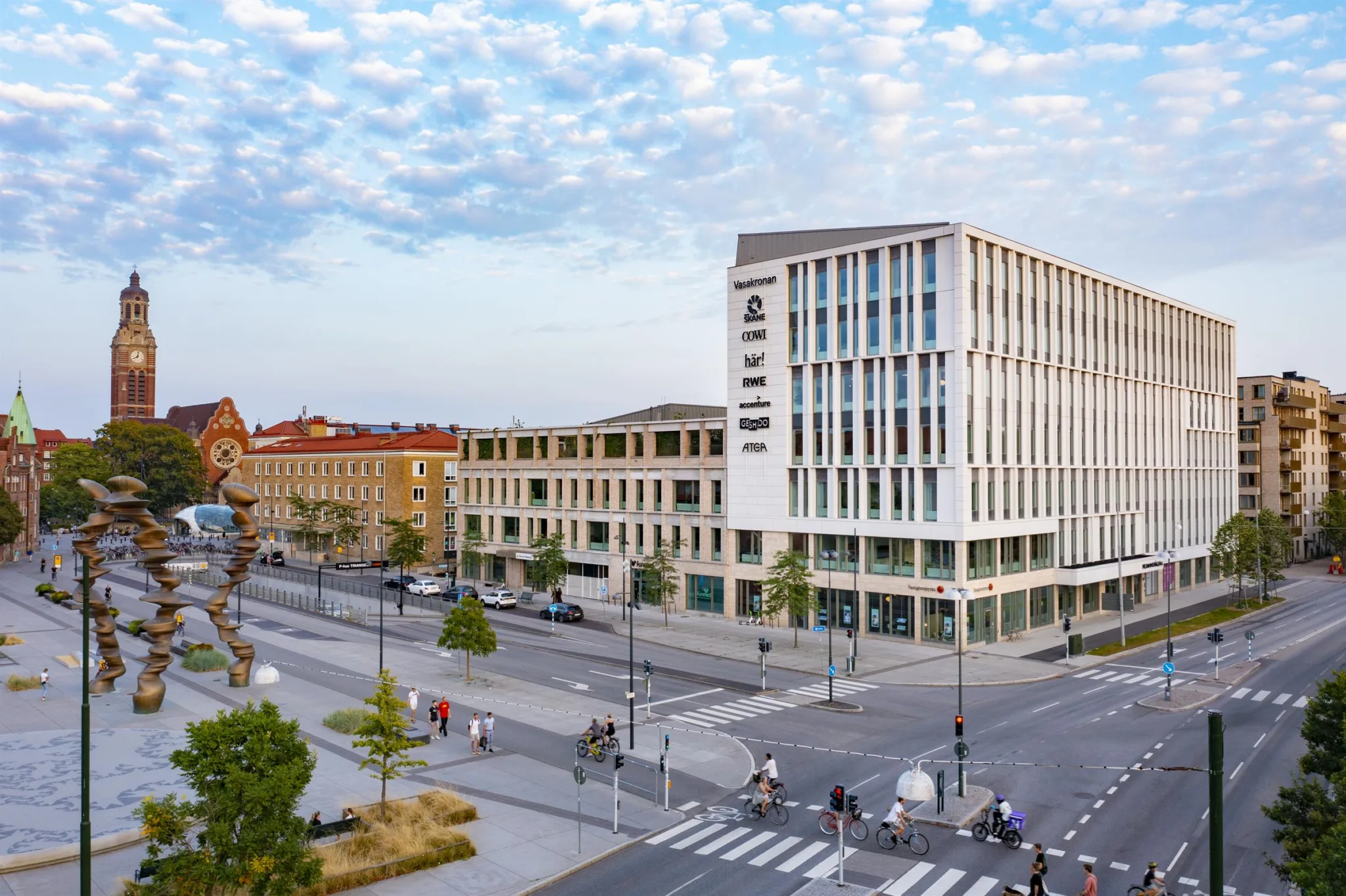 En modern stadsbyggnad i flera våningar med stora fönster och en öppen gata med övergångsställen framför.