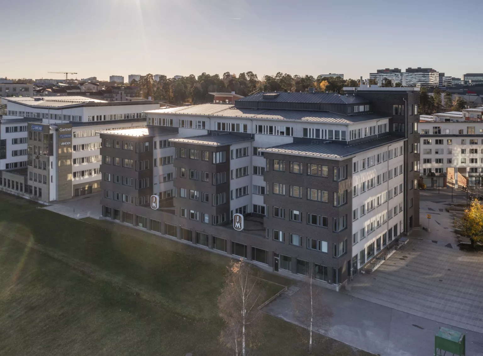 En byggnad med mörk fasad, grön gräsmatta i förgrunden och klar himmel i bakgrunden.