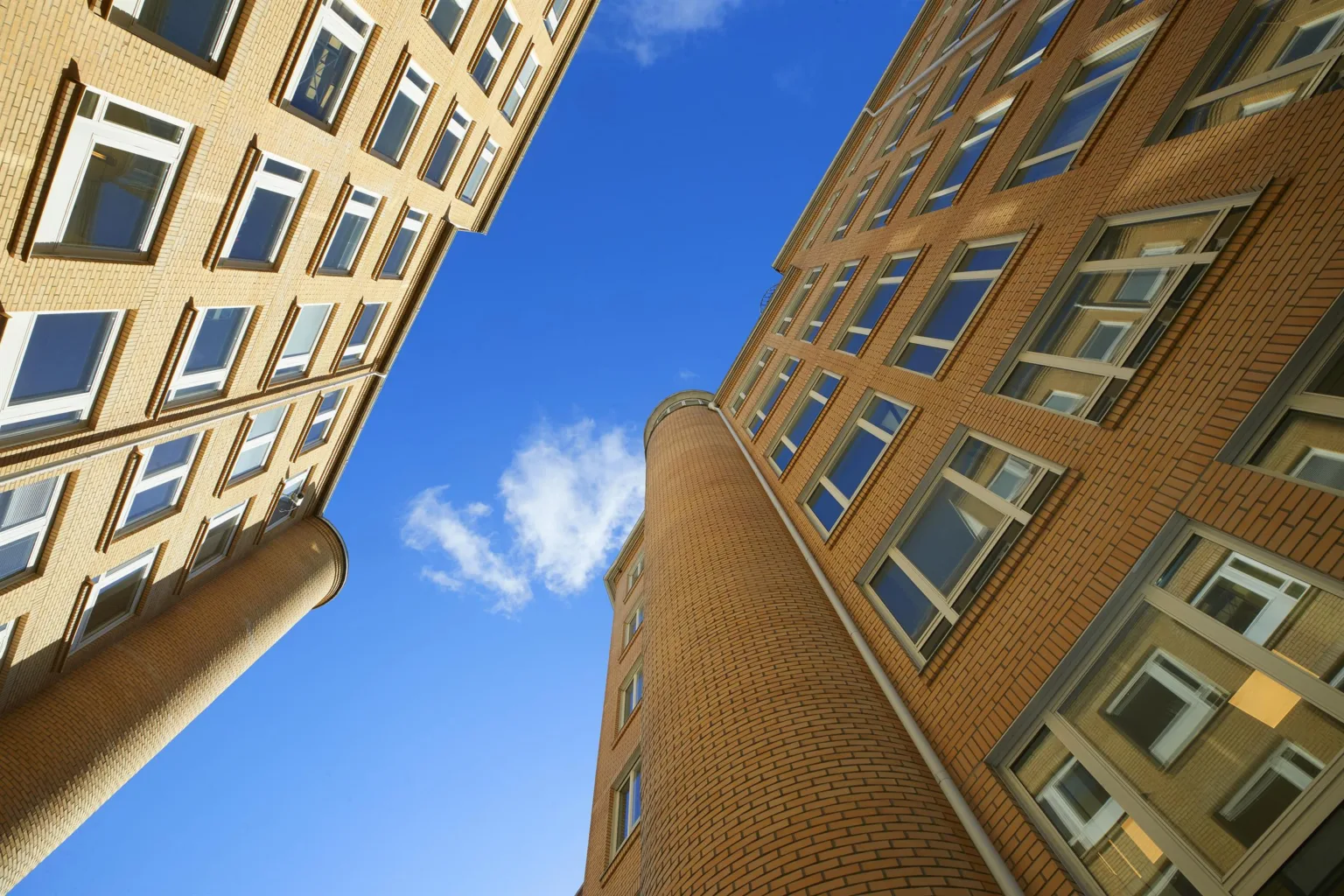 5. Perspektivvy uppåt av tegelbyggnader med många fönster mot en blå himmel.