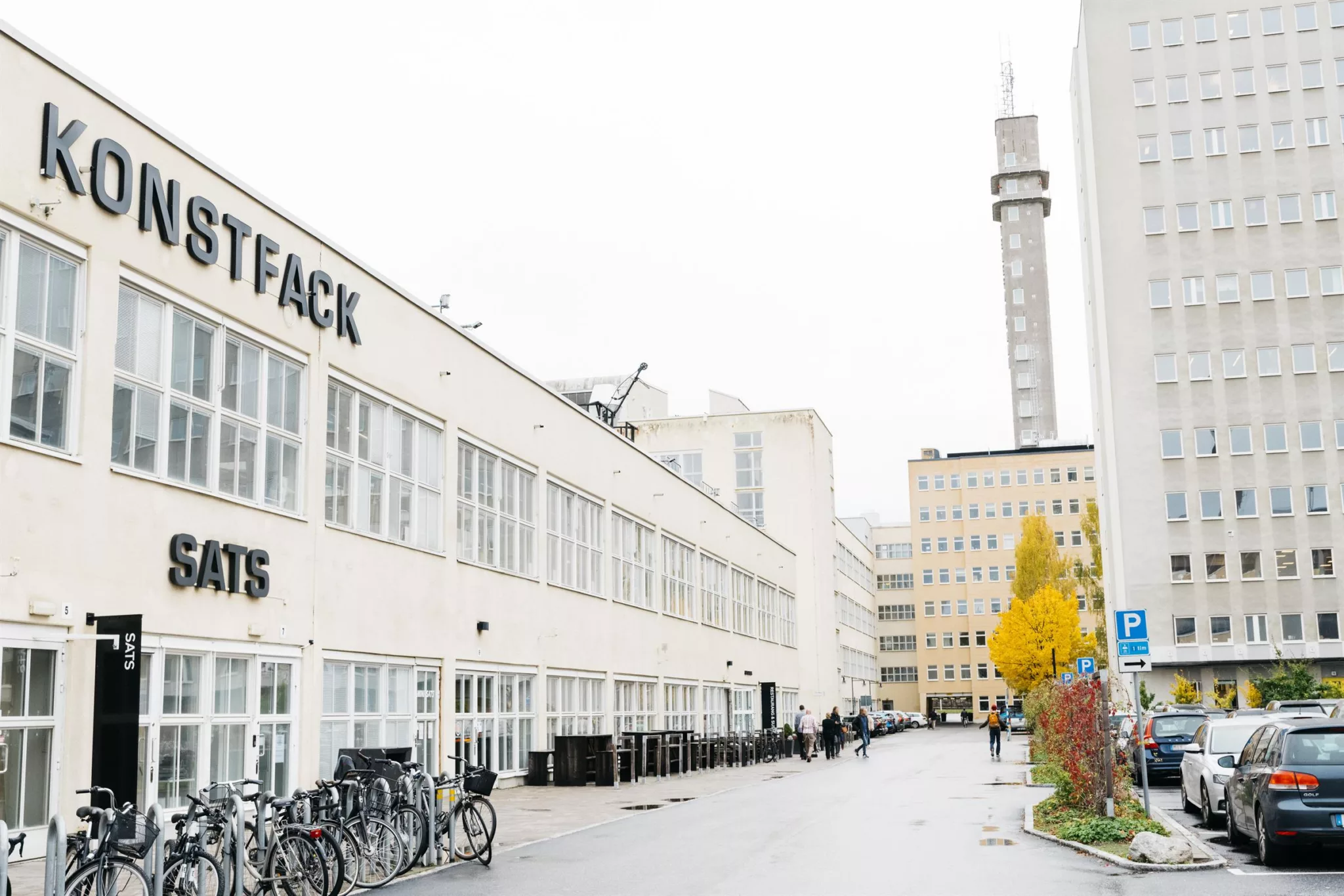 2. En vit byggnad med texten "STHLMSTUDIOS" på fasaden, en cykelparkering och Telefontornet synligt i bakgrunden.