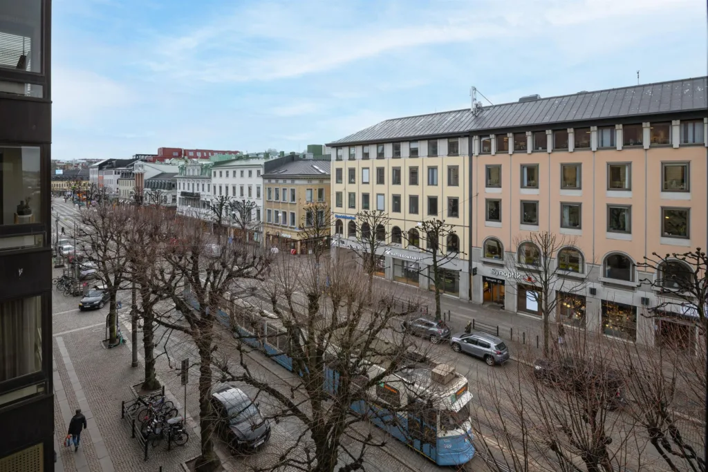 1. En stadsgata med spårvagn, träd och flerfärgade byggnader i bakgrunden.