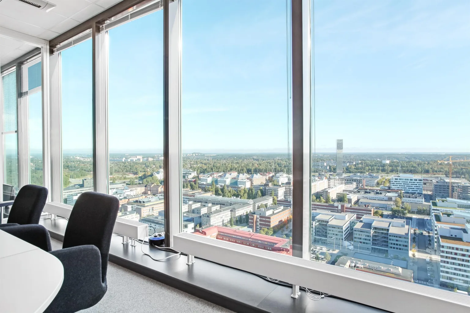 3. Utsikt från en hög byggnad med stora fönster som visar en stadsmiljö och blå himmel.