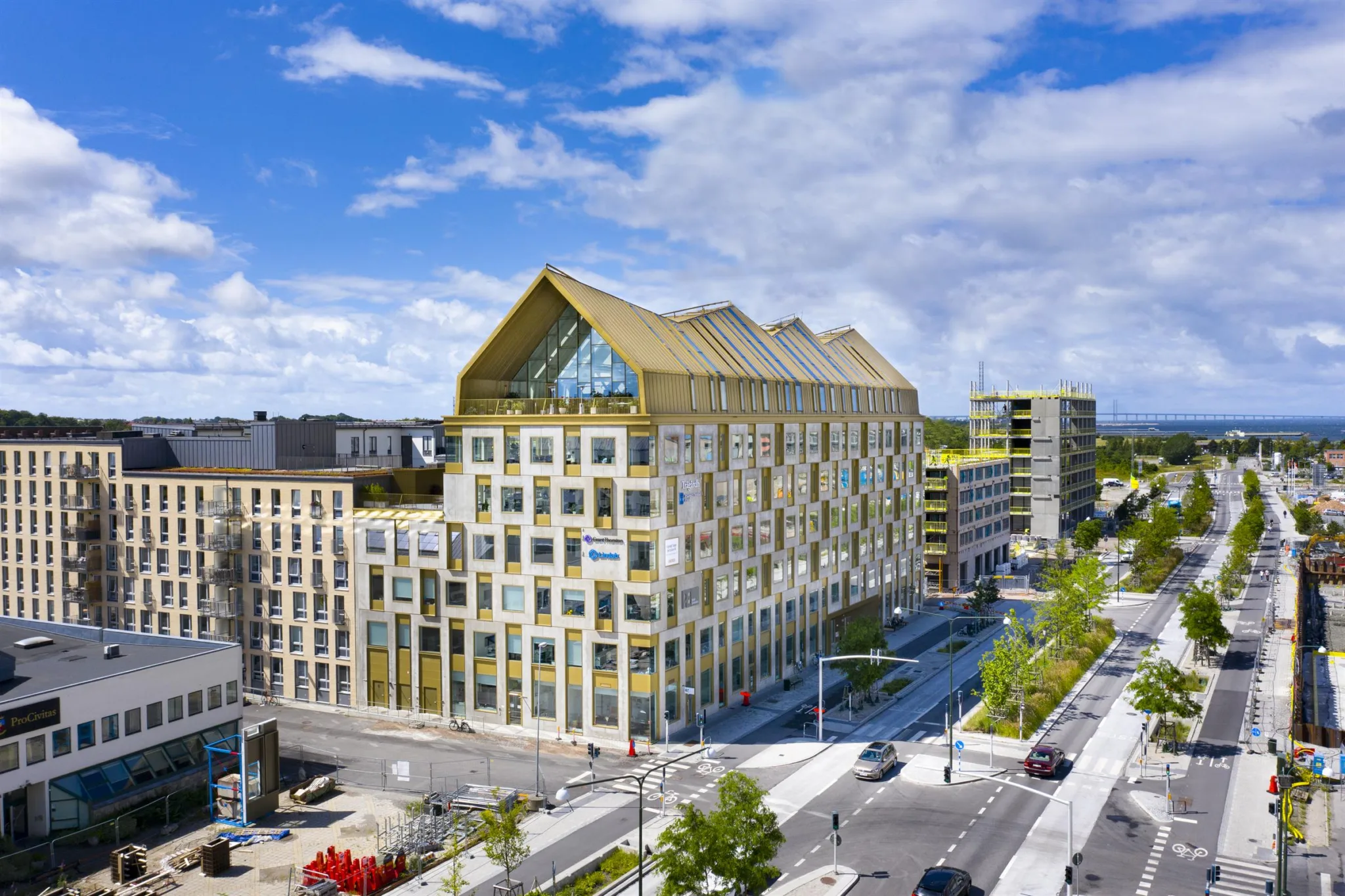 5. En modern byggnad med guldfärgat tak och glasfönster omgiven av stadsmiljö och grönska.