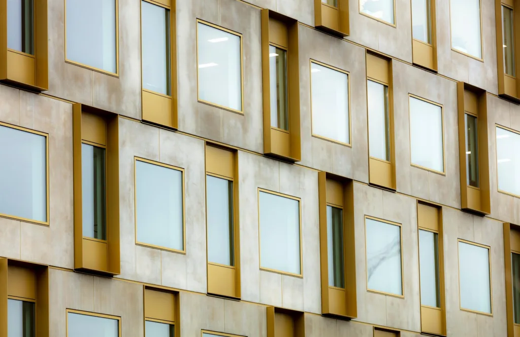 Byggnad med fasad av guldfärgade ramar och glasfönster i geometriskt mönster.