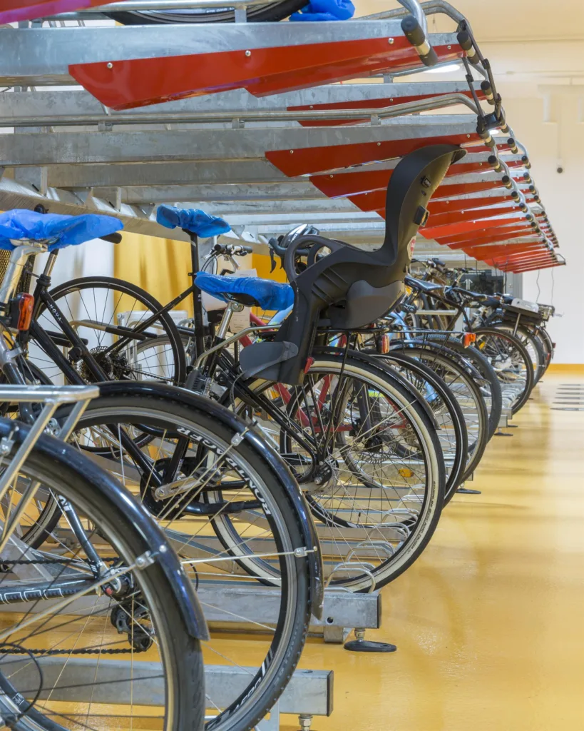 En rad parkerade cyklar i en cykelställning inomhus med färgglada detaljer.