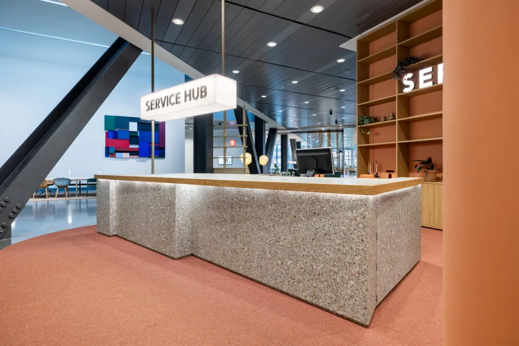 En receptionsdisk med skylten "Service Hub" ovanför, modern design och hyllor i bakgrunden.