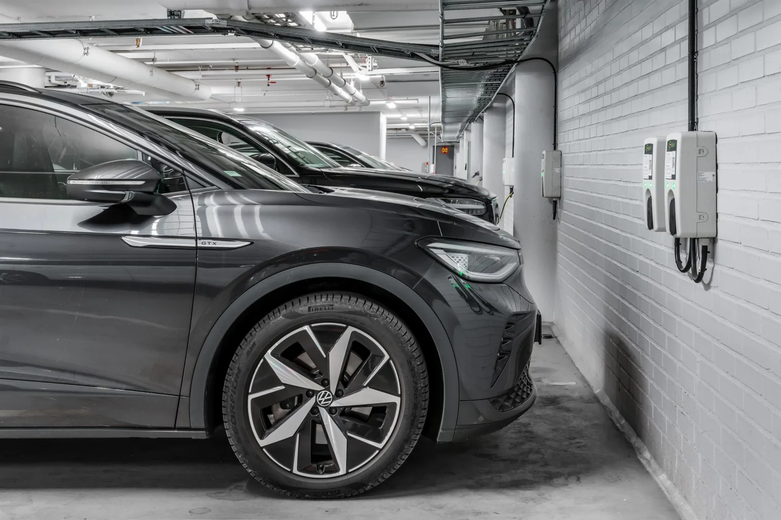 5. Svart elbil parkerad vid laddstation i en ljus och modern garageanläggning.