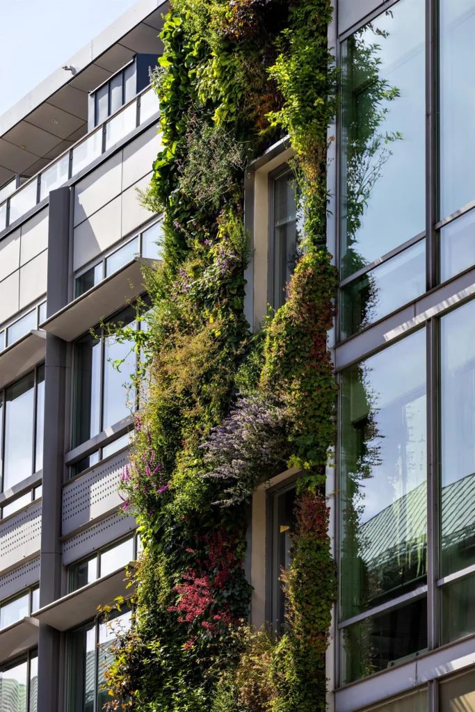 Fasad av en byggnad med vertikal trädgård täckt av grönska och blommor.