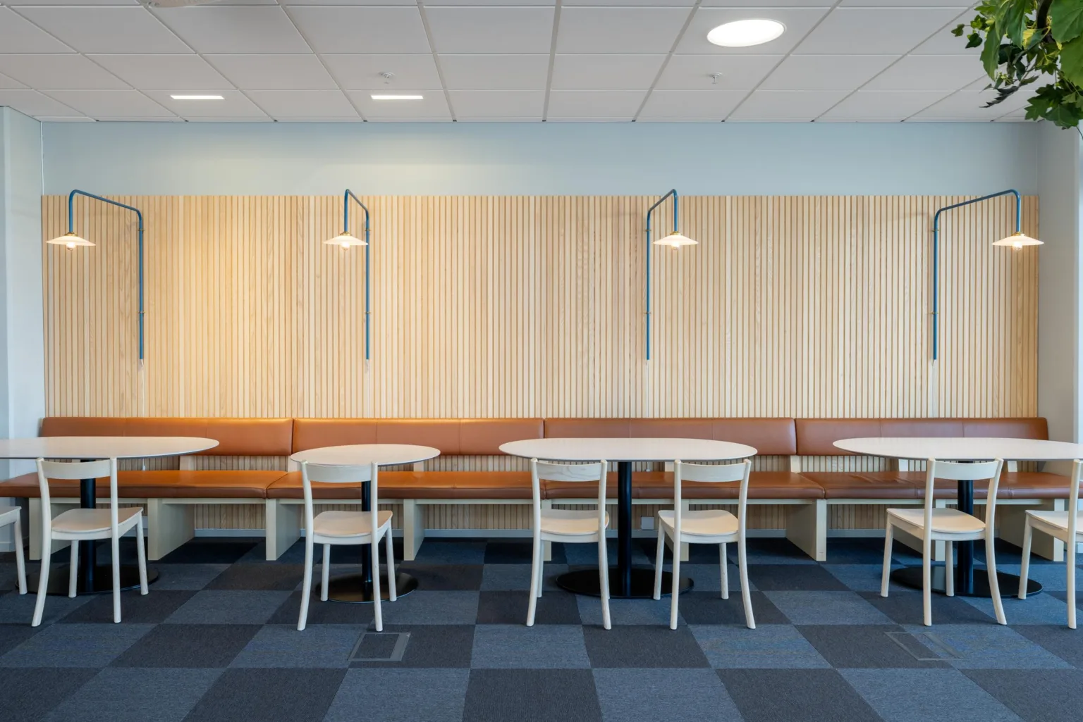 1. Restaurangområde med träpaneler, taklampor, bord och stolar samt grått rutigt golv.