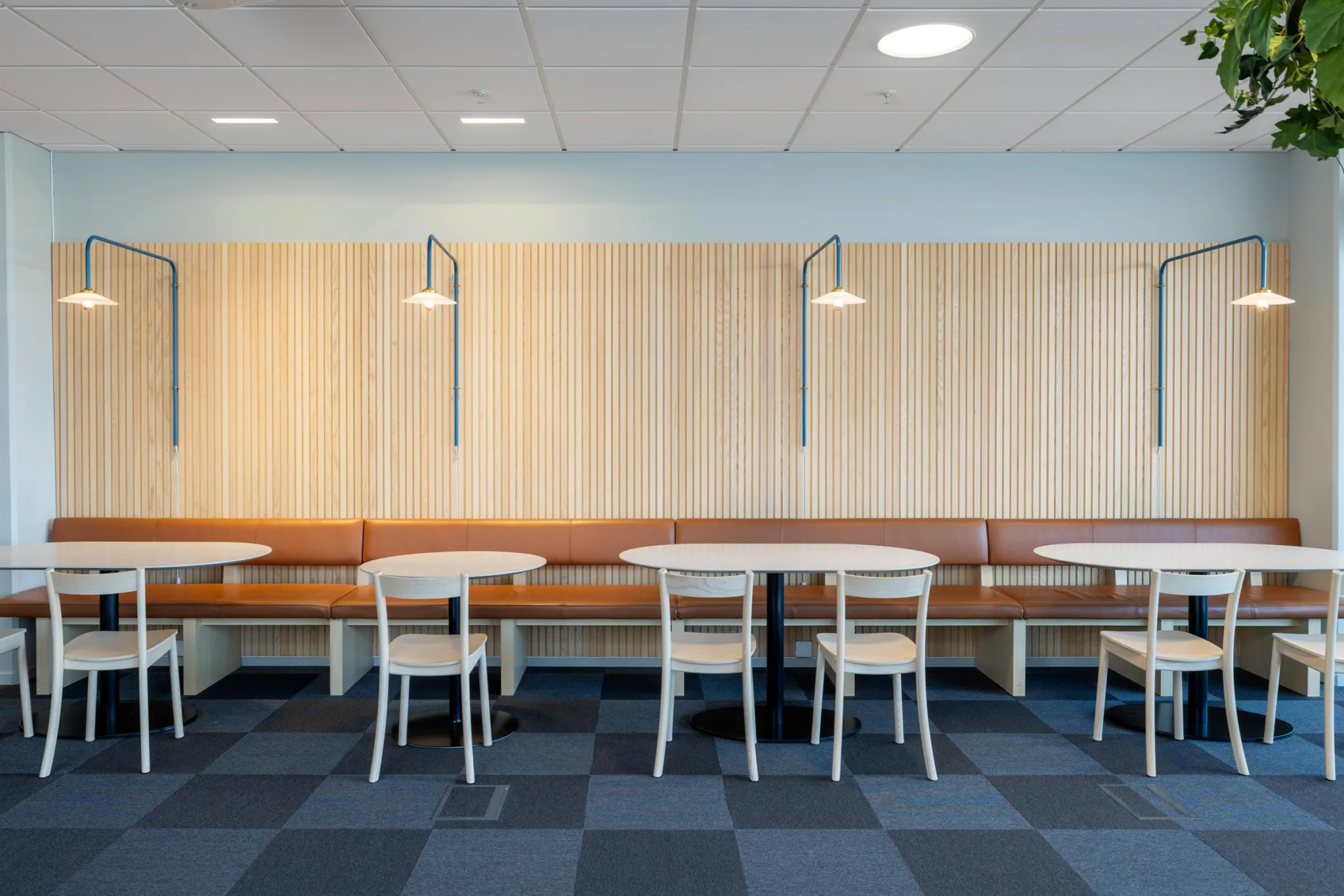 1. Restaurangområde med träpaneler, taklampor, bord och stolar samt grått rutigt golv.